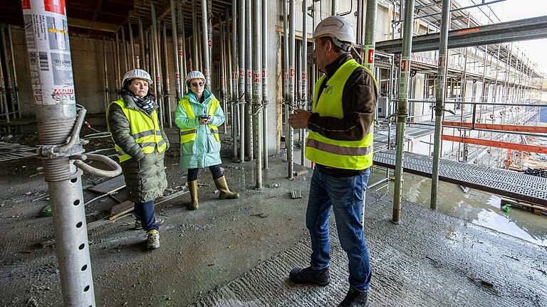 Klinikreferent René A. Bostelaar führt Landrätin Sabine Sitter (links) und Redakteurin Lena Schwaiger durch die Baustelle. Noch stehen Baustützen in den Stockwerken, durch die man sich wie durch ein Labyrinth bewegen muss.