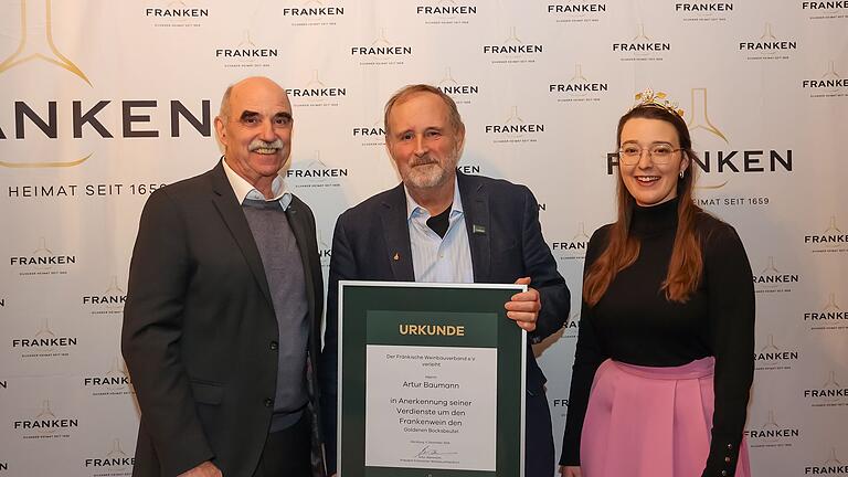 Der Präsident des Fränkischen Weinbauverbands Artur Steinmann (links) übergibt zusammen mit der 66. Fränkischen Weinkönigin Lisa Lehritter (rechts) an Artur Baumann (in der Mitte) den Goldenen Bocksbeutel, die höchste Auszeichnung der fränkischen Weinwirtschaft.