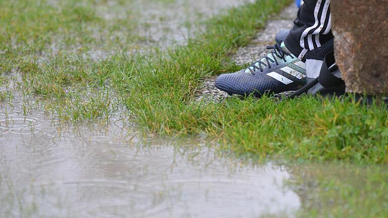 Auf einem Fußballplatz hat sich eine große Pfütze gebildet.