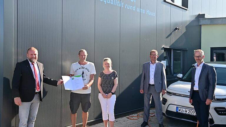 Landrat Thomas Eberth übergibt die Urkunde des Umwelt- und Klimapaktes Bayern an Martin Weber von Martin Weber Haustechnik und Jacqueline Seufert. Es gratulierten Waldbüttelbrunns Bürgermeister Klaus Schmidt und Kreisentwicklungsleiter Michael Dröse.