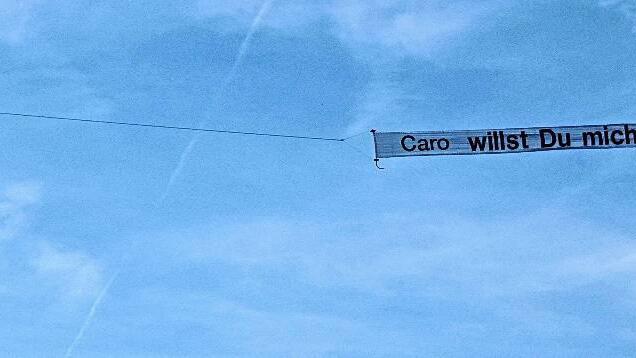 &bdquo;Caro willst Du mich heiraten&ldquo; steht auf dem Schleppbanner, das ein Ultraleichtflieger durch die luftigen Höhen über der Homburg bei Gössenheim zieht. Gemeint ist Carolin Röhner, deren Freund Michael Feser sich diese besondere Art des Heiratsantrags ausgedacht hatte. Sein Fliegerfreund Patrick Hagedorn wirft zudem einen Strauß roter Rosen ab. Die Überraschung glückt &ndash; und die künftige Braut sagt Ja.