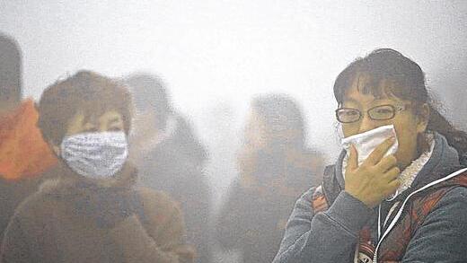 Mundschutz gegen den Smog: Frauen warten auf einen Bus in der chinesischen Stadt Harbin.