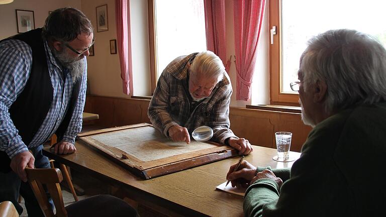 Der Adelsberger Julius Sitzmann (Mitte) versucht alte handschriftliche Seiten zu entziffern. Der Seifriedsburger Hahn-Wirt Tino Görtler (links) und der Langenprozeltener Ulf Fischer sind ganz Ohr.