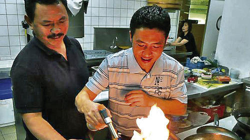 Mit dem Gasbrenner flambiert Tashi Tamazu den hauchdünn geschnittenen Peterfisch, links Kham-Inhaber Namkha Dorjee.