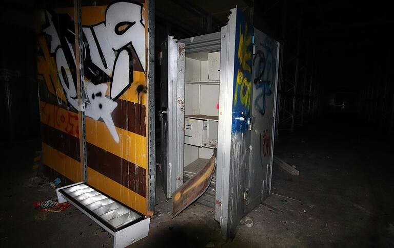 Ein geöffneter Tresor steht inmitten der großen Lagerhalle, längst seiner einstigen Schätze beraubt.