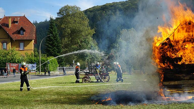 Eine Schauübung mit brennendem Häuschen vor dem Festplatz an der Turnhalle, Löschübung mit alter Handpumpe.