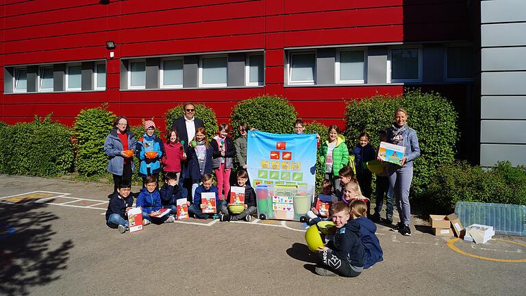 Neben Rektor Roland Wagner, Klassenlehrerin Jutta Hohloch  und AOK-Ernährungsberaterin Ulrike Jaques (rechts) freuen sich die Kinder der Klasse 3b der Grundschule Würzburg-Lengfeld über die Kochbox der AOK.