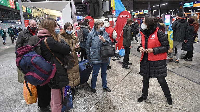 Eine Mitarbeiterin der Caritas (rechts) spricht mit Frauen und einem Mann aus der Ukraine, die nach ihrer Flucht am Münchner Hauptbahnhof angekommen sind. Wer sich engagiert, hilft einerseits den notleidenden Menschen und verringert gleichzeitig das Empfinden von Ohnmacht und Nutzlosigkeit.