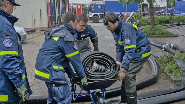 Einsatzkräfte des Technischen Hilfswerks schleppen ihre Ausrüstung zum Einsatzort.