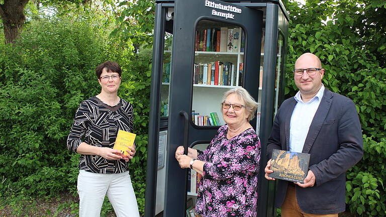 Eine alte Telefonzelle haben 2022 die inzwischen verstorbene Patricia Reinhart (links), ihr Ehemann Erwin (nicht auf dem Foto) sowie Irmgard Manger (Mitte) zur 'Büchertauschbörse' umfunktioniert.  Bürgermeister Tobias Seufert freute sich über die tolle Aktion.