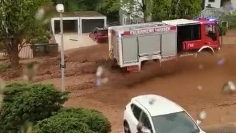 Braune Wassermassen auf den Straßen: Starkregen hat am Mittwochnachmittag den Bad Kissinger Ortsteil Hausen überschwemmt. Ein Feuerwehrauto fährt durch das 30 Zentimeter tiefe Wasser zu einer Einsatzstelle.  Foto: Martina Schneider       -  Braune Wassermassen auf den Straßen: Starkregen hat am Mittwochnachmittag den Bad Kissinger Ortsteil Hausen überschwemmt. Ein Feuerwehrauto fährt durch das 30 Zentimeter tiefe Wasser zu einer Einsatzstelle.  Foto: Martina Schneider