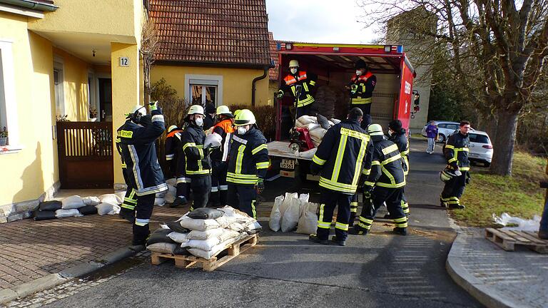 An der Brücke in Obervolkach errichten die Feuerwehrleute einen Notwasserabflussweg.