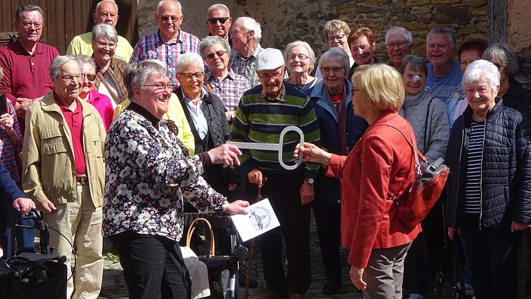 Helga Schubert, Leiterin des „Club 60“ Uettingen, überreicht im Rahmen eines Ausfluges nach Kleinlangheim Monika Conrad symbolisch den Schlüssel für die Wohnung in der ehemaligen Schule „Neue Mitte Uettingen“. Die tatsächliche Übergabe fand am darauffolgenden Tag in Uettingen statt.