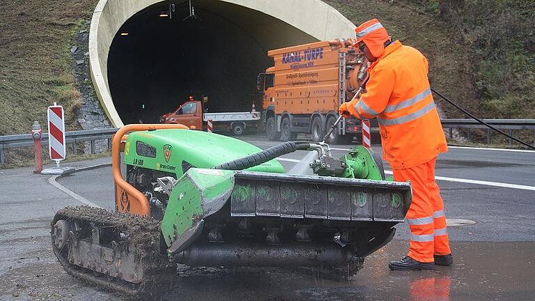 Ein Mitarbeiter der Autobahnmeisterei säubert einen ferngesteuerten Mähroboter, mit dem die steilen Grünflächen oberhalb der Tunnelportale kurz gehalten werden.