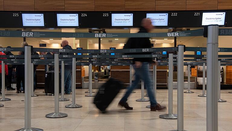 BER - Ein Reisender geht mit einem Koffer zu einem Check-in-Schalter von Eurowings. BER - Ein Reisender geht mit einem Koffer zu einem Check-in-Schalter von Eurowings.