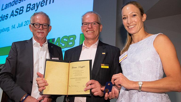 Thomas Klüpfel erhält aus den Händen von Christine Theiss und Hans-Ulrich Pfaffmann (links) das Samariter-Ehrenkreuz in Gold. Foto: Timm Schamberger Thomas Klüpfel erhält aus den Händen von Christine Theiss und Hans-Ulrich Pfaffmann (links) das Samariter-Ehrenkreuz in Gold. Foto: Timm Schamberger