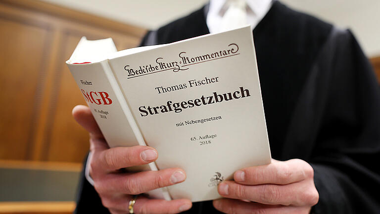 Ein Richter im Gerichtssaal hält das Strafgesetzbuch in der Hand (Symbolfoto).
