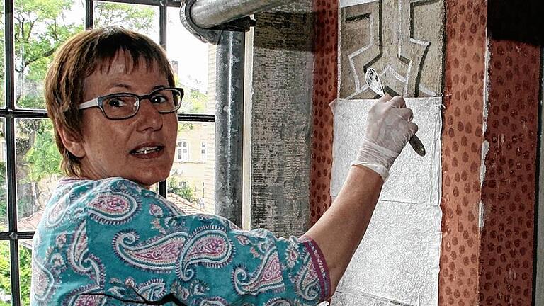 Restauratorin Heike Pfund säubert die Wände an einem Fensterbogen im Hauptschiff.