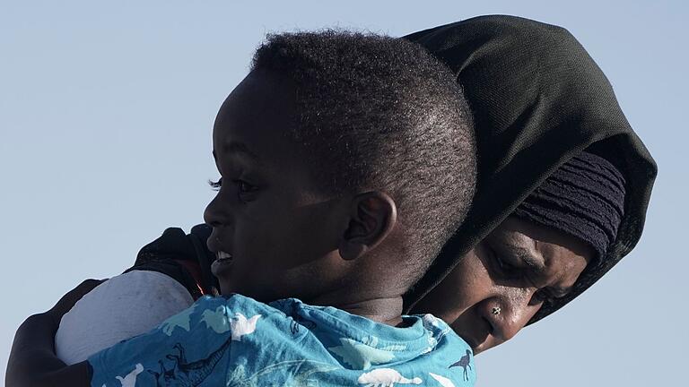 Konflikt im Sudan.jpeg       -  Eine Frau aus dem Sudan trägt ihren Sohn, während sie von Bord der USNS Brunswick gehen.