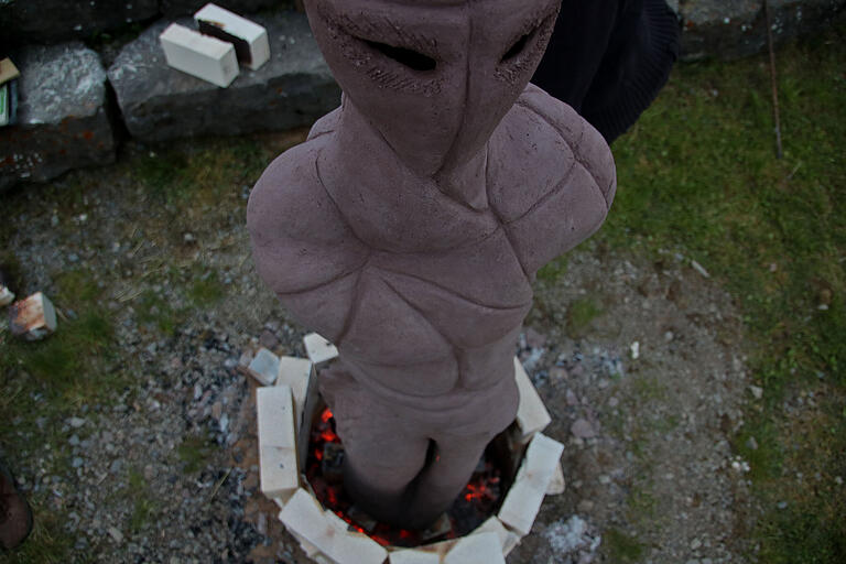 In Vorbereitung des Brennvorgangs wird die jeweilige Figur mit den ersten Reihen von Schamottsteinen umstellt und die erste Glut aus Grillkohle zwischen der Figur und den Schamottsteinen eingebracht. Diese Glutschicht sorgt dafür, dass die Restfeuchte langsam aus dem Tongebilde entweicht. In Vorbereitung des Brennvorgangs wird die jeweilige Figur mit den ersten Reihen von Schamottsteinen umstellt und die erste Glut aus Grillkohle zwischen der Figur und den Schamottsteinen eingebracht. Diese Glutschicht sorgt dafür, dass die Restfeuchte langsam aus dem Tongebilde entweicht.