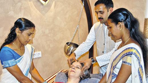 Asiatische Heilkunst: Ayurveda-Arzt Jobin Joy Madukkakuzhy mit seinen indischen Helferinnen bei der Behandlung einer Patientin. Foto: Dobschütz Asiatische Heilkunst: Ayurveda-Arzt Jobin Joy Madukkakuzhy mit seinen indischen Helferinnen bei der Behandlung einer Patientin. Foto: Dobschütz