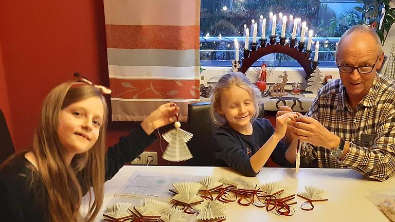 Hans Kober bastelt zusammen mit seinen Enkelinnen Helena  und Rosalie  Weihnachtsengel aus ausgedienten Gesangsbüchern.       Foto: Isabell Gerr       -  Hans Kober bastelt zusammen mit seinen Enkelinnen Helena  und Rosalie  Weihnachtsengel aus ausgedienten Gesangsbüchern.       Foto: Isabell Gerr