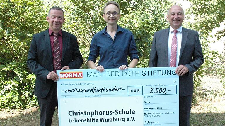 Stefan Thiel (von links), Schulleiter Christoph Schwind und Jörg Hueber mit dem Scheck der Manfred-Roth-Stiftung.