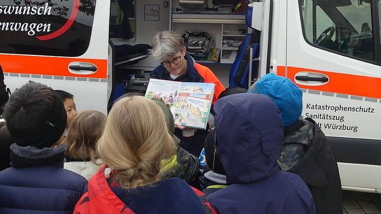 Malteserin Christina Gold las den Kindern aus dem Buch 'Mini muss ins Krankenhaus' vor und zeigte ihnen anschließend den Herzenswunsch-Krankenwagen.