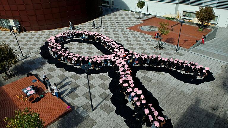 Schüler bilden eine menschliche rosa Schleife       -  Die rosa Schleife ist ein internationales Symbol, dass Bewusstsein für Brustkrebs schaffen will. Eine von acht Frauen ist im Laufe ihres Lebens davon betroffen.