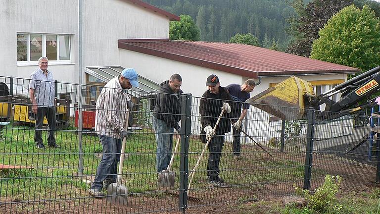 Asylbewerber helfen beim Zaunbau       -  (wsch)   Zwei Männer der in Gräfendorf lebenden asylsuchenden Familien aus Syrien und Afghanistan leisten einen gesellschaftlichen Beitrag im Bauhof. Mit Bauhofleiter Gotthard Schwender und Udo Henning füllten sie den Boden um die Pfosten des neuen Sicherheitszaunes am Kindergarten auf, verfestigten ihn, rechten ihn eben und entfernten Steine. Der kunststoffbeschichtete Zaun umzäunt den Spielbereich der Kinderkrippengruppe und der Kindergartenkinder mit Vorschulkinder an der Grundschule. Den Zaun hat die Gemeinde finanziert. Bürgermeister Alfred Frank freute sich über die gute und harmonische Zusammenarbeit und bedankte sich bei den Asylbewerber für ihre Unterstützung.