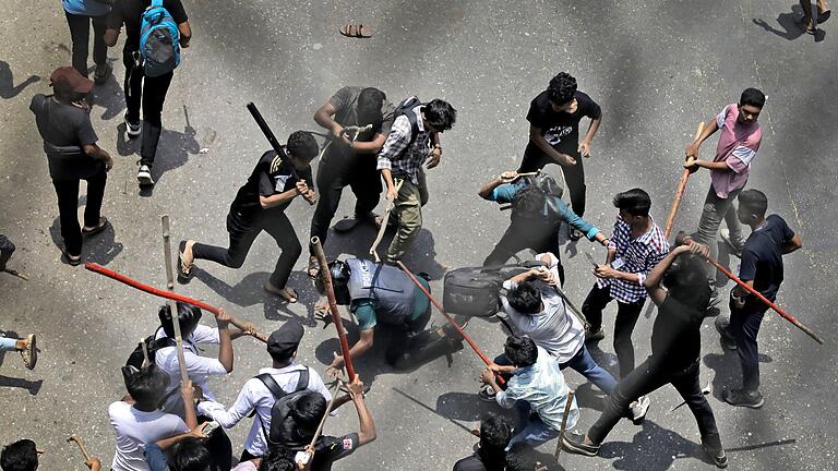 Studentenproteste in Bangladesch       -  Studenten schlagen einen Polizisten mit Stöcken