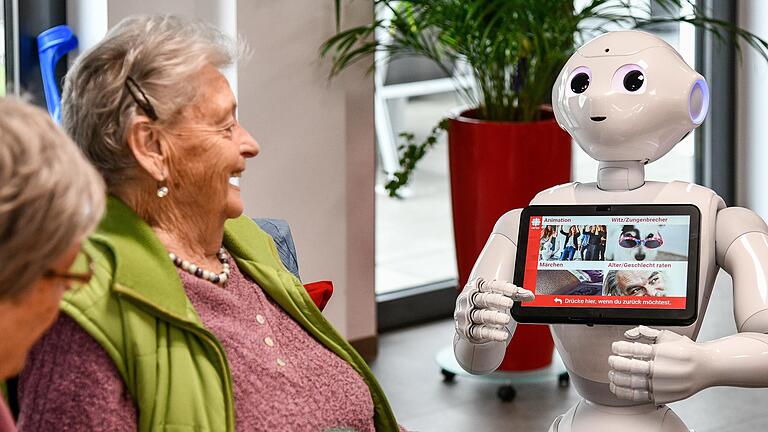 Nur 1,20 Meter groß und doch stets im Mittelpunkt: Seit Januar rollt der Roboter Pepper durch die Tagespflege der Caritas-Sozialstation in Erlenbach am Main (Lkr. Miltenberg). Im Bild ist er mit der 86-jährigen Annemarie Wöber zu sehen.