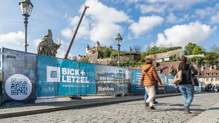 Fußgänger auf der Alten Mainbrücke in Würzburg laufen derzeit an einem langen Zaun mit Sichtschutz entlang. Fußgänger auf der Alten Mainbrücke in Würzburg laufen derzeit an einem langen Zaun mit Sichtschutz entlang.