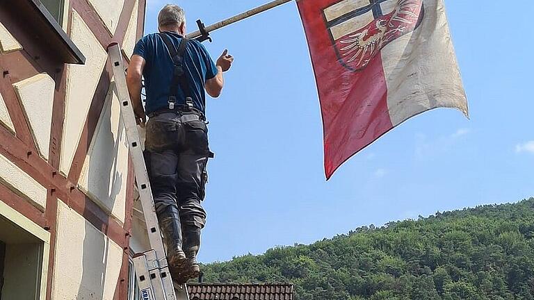 uwejakobshisstdorffahnealszeichennichtaufzugeben - „Ein Zeichen, dass wir nicht aufgeben“: Uwe Jakobs hisst die Ahrweiler Flagge. uwejakobshisstdorffahnealszeichennichtaufzugeben - „Ein Zeichen, dass wir nicht aufgeben“: Uwe Jakobs hisst die Ahrweiler Flagge.