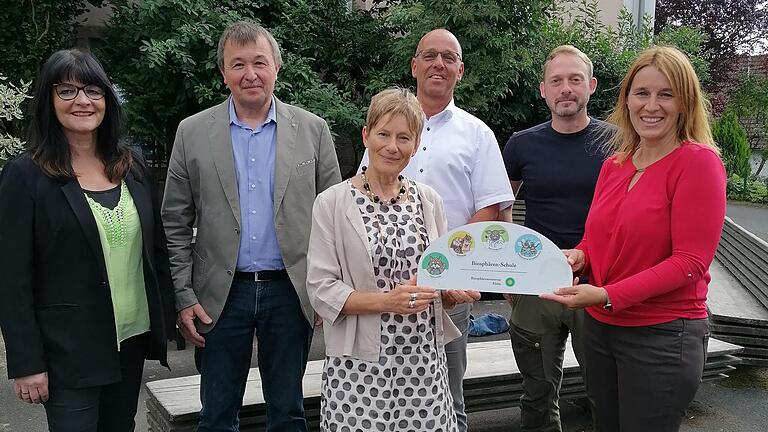 Nun ist die Grundschule Riedenberg eine 'Biosphären-Schule'. Das Zertifizierungsschild wurde Rektorin Christiane Helfrich (rechts) von der stellvertretenden Dienstellenleiterin des Biosphären-Reservates Rhön, Doris Pokorny überreicht. Über die Aus...       -  Nun ist die Grundschule Riedenberg eine 'Biosphären-Schule'. Das Zertifizierungsschild wurde Rektorin Christiane Helfrich (rechts) von der stellvertretenden Dienstellenleiterin des Biosphären-Reservates Rhön, Doris Pokorny überreicht. Über die Auszeichnung freuen sich Schulrätin Birgit Herré(von links), Riedenbergs Bürgermeister Roland Römmelt, Wildfleckens Bürgermeister Gerd Kleinhenz und d Alexander Fromm,Mitarbeiter des Umweltteams Haus der Schwarzen Berge.