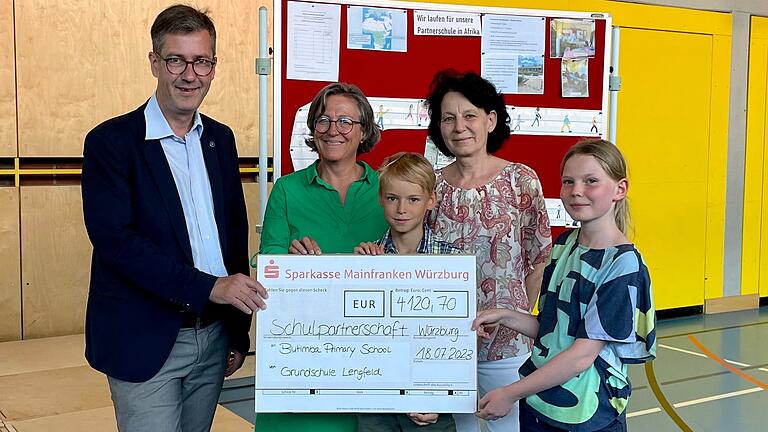 Oberbürgermeister Schuchardt und Monika Kraft (Stadt Würzburg, Sozialreferat) nehmen&nbsp;symbolisch den Spendenscheck für die Butimba Primary School von&nbsp; Lennart, Gabriele Waag (Schulleiterin) und Frida entgegen.