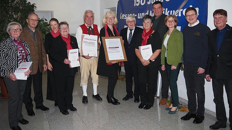 Ehrung zum runden Jubiläum des Gesang- und Musikvereins: (von links) Jubilarin Maria Schamberger, Ehrenchorleiter Manfred Hornung, Chor-Dirigentin Paula Braedt, Jubilarin Christine Fuchs, Eugen Wild, zweiter Vorsitzender (Abteilung Musik), erste Vorsitzende Monika Rödemer (Abteilung Chor), Friedhelm Brusniak, Präsident des Fränkischen Sängerbunds, Jubilarin Ulrike Groß, Bürgermeister Thomas Hemmerich, stellvertretende Landrätin Bettina Bärmann sowie, als Ortsgeistliche, Markus Grzibek und Martin Bauer.