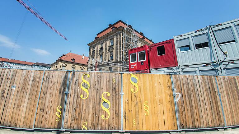 Durchblick auf die Justiz-Baustelle: Gucklöcher in Paragrafenzeichen im Bauzaun.