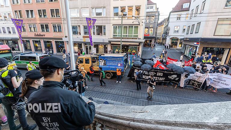 Nach dem Einsatz von Pyrotechnik begann die Polizei die Demo in der Würzburger Innenstadt zu filmen. Teilnehmde schirmten sich mit Regenschirmen dagegen ab.