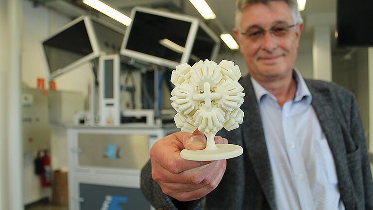 All diese Zahnräder drehen sich, alles wurde aus einem Guss hergestellt: SKZ-Bereichsleiter Georg Schwalme mit einem im 3D-Verfahren gefertigten Modell aus Kunststoff. Hinten ist der Drucker zu erkennen. Das Modell wäre auf herkömmlichem Weg viel umständlicher herzustellen gewesen und zeigt, was mit 3D-Druck mittlerweile möglich ist. All diese Zahnräder drehen sich, alles wurde aus einem Guss hergestellt: SKZ-Bereichsleiter Georg Schwalme mit einem im 3D-Verfahren gefertigten Modell aus Kunststoff. Hinten ist der Drucker zu erkennen. Das Modell wäre auf herkömmlichem Weg viel umständlicher herzustellen gewesen und zeigt, was mit 3D-Druck mittlerweile möglich ist.