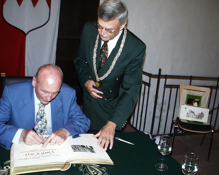 Der Fußballweltmeister von 1954, Horst Eckel, trägt sich am 14. Mai 2004 ins Goldene Buch der Stadt Gerolzhofen ein. Rechts im Bild der damalige Bürgermeister Hartmut Bräuer.