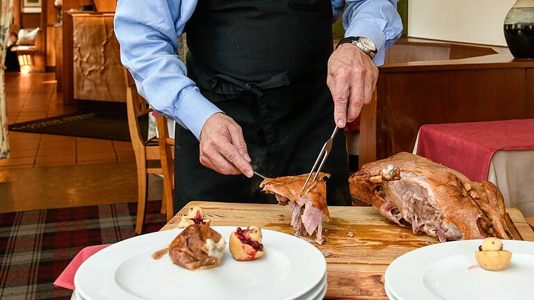 Im Gasthof Bären in Randersacker tranchiert der Inhaber Stefan Morhard eine Gans für vier Gäste.