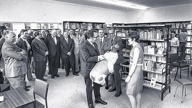 Eröffnung der ersten Stadtteilbücherei in Heidingsfeld: Oberbürgermeister Klaus Zeitler übergibt Zweigstellenleiterin Heidi Hederich ein Sitznashorn. Dazwischen mit verschränkten Armen der damalige Gesamtbibliotheksleiter Karl-Heinz Pröve.