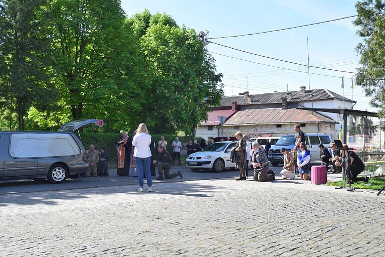 Bei einer Gedenkfeier für einen im Krieg gefallenen Soldaten aus Jaworiw knien Angehörige neben dem Leichenwagen.