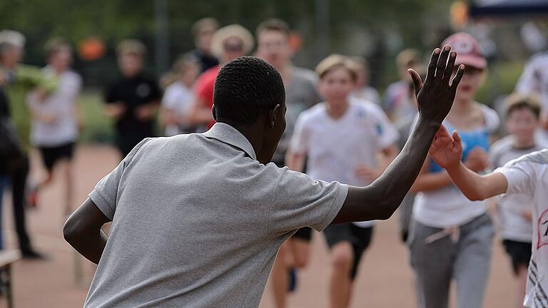 Deutschhaus Gymnasium Spendenlauf       -  High-Five: Madukulu Madukulu begrüßt die Schüler bei ihrem Einlauf auf dem Sportgelände des Deutschhaus-Gymnasiums. Der 28-Jährige ist Sozialarbeiter in Mwanza und wird zukünftig auch an dem neuen Sportzentrum arbeiten, für das beim Spendenlauf gesammelt wird.