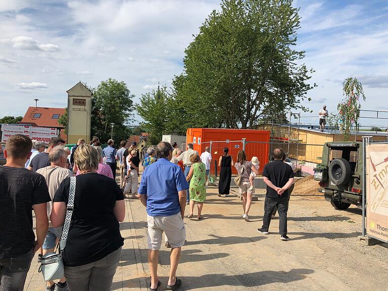 Zimmerer Michael Weckbart spricht beim Richtfest des Kindergartenneubaus in Fuchsstadt den Richtspruch. Die Bürgerinnen und Bürger schauen ihm zu.