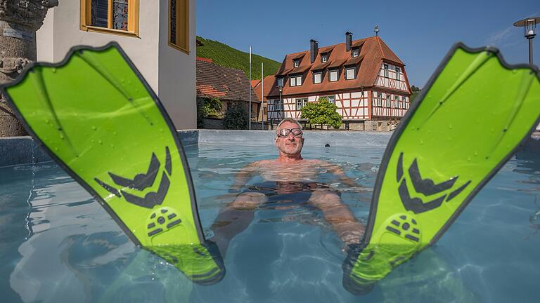 Bei hohen Temperaturen um die 30 Grad kühlt sich ein Mann in einem Brunnen in Escherndorf ab. Aber es gibt weitere Möglichkeiten, sich im Landkreis Kitzingen zu erfrischen und der Hitze zu entfliehen.