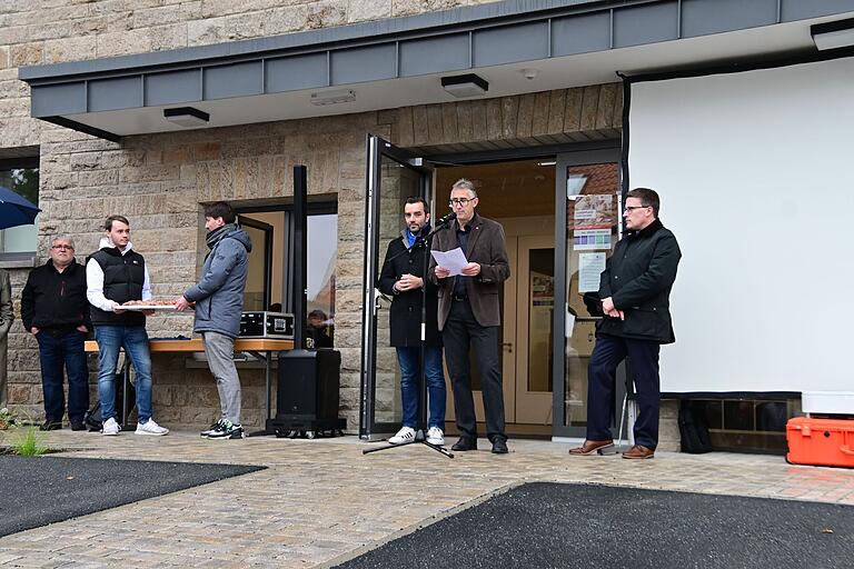 Architekt Albert Kastner sprach am Mikrofon von der besonderen Herausforderungen beim Umbau des ehemaligen Kindergartens in ein Ärzte- und Seniorenhaus, während Landrat Christoph Schauder (rechts) und Bürgermeister Johannes Leibold (an der Tür) zuhörten.