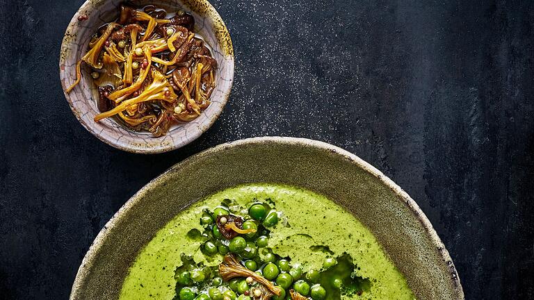Grüne Erbsensuppe mit eingelegten Pfifferlingen       -  Einen schönen Mix aus Aromen und Texturen kreierte Martin Nordin: Auf die pürierte und heiße Erbsensuppe kommen ein paar Erbsen sowie eingelegte Pfifferlinge.