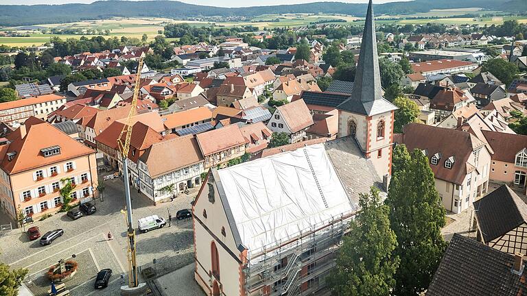 Das Dach der Hofheimer Stadtpfarrkirche St. Johannes der Täufer wird aktuell saniert. Mit einer weißen Plane ist ein Teil des Dachs abgedeckt.